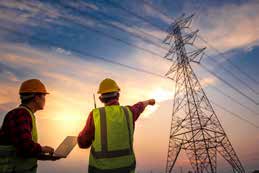 Engineers looking towards a transmission tower at sunset.