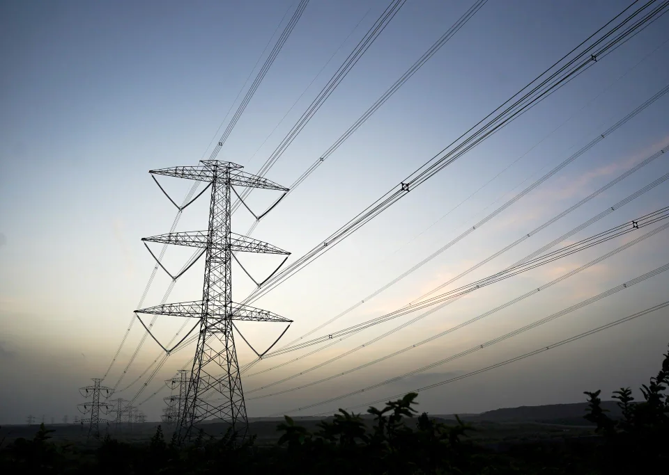 Transmission tower and conductors silhouetted against a sunset sky